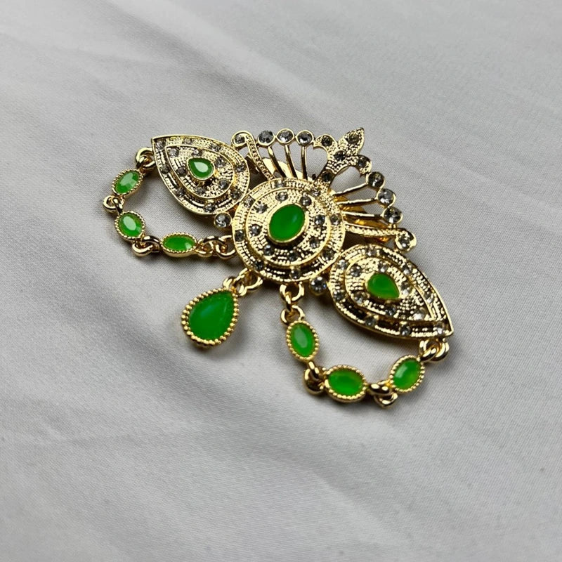 Broche orientale dorée avec pierres vertes vue en angle pour caftan marocain et tenue de cérémonie