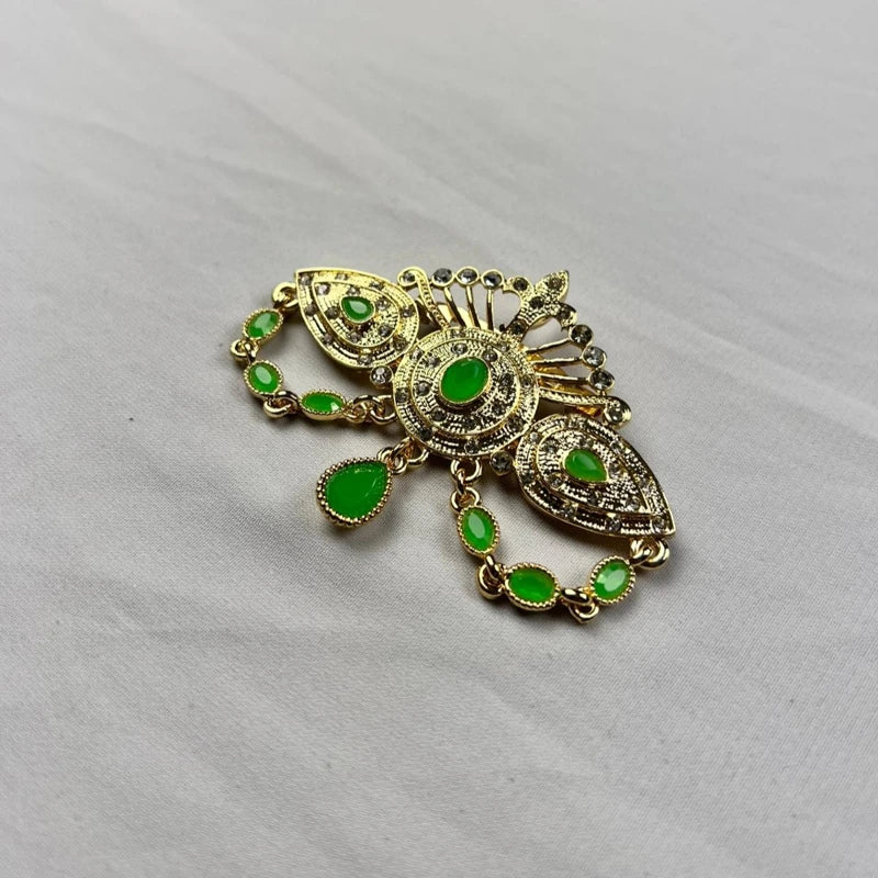 Broche orientale dorée avec pierres vert émeraude et détails strass pour caftan marocain