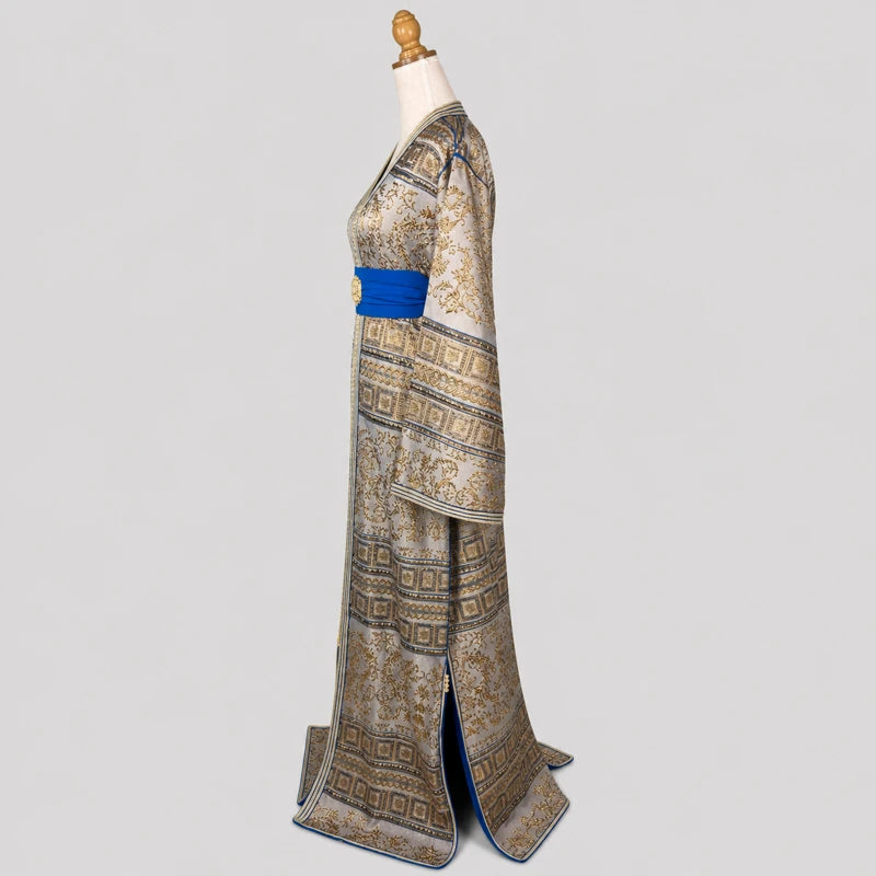 Vue de profil du caftan brocard vintage gris argenté et doré avec manches larges, motifs orientaux raffinés et ceinture bleue élégante.