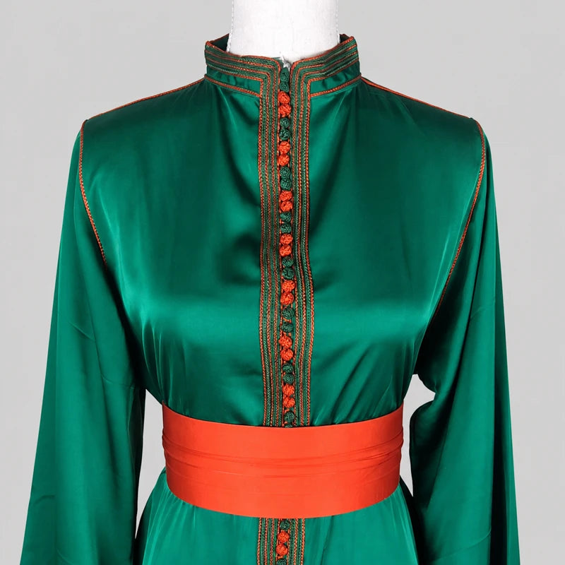 Détail d’un caftan en drap de soie vert profond avec col brodé et ceinture orange satinée, robe marocaine élégante aux finitions raffinées pour mariage et cérémonie orientale.