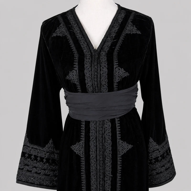 Détail d’un caftan femme en velours noir brodé avec ceinture satinée et finitions artisanales élégantes, robe marocaine raffinée pour mariage, soirée et cérémonie orientale.