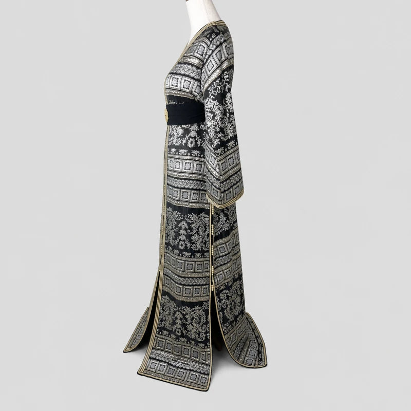 Vue de profil d’un caftan marocain brocart noir vintage pour femme avec motifs argentés raffinés et bordures dorées élégantes.