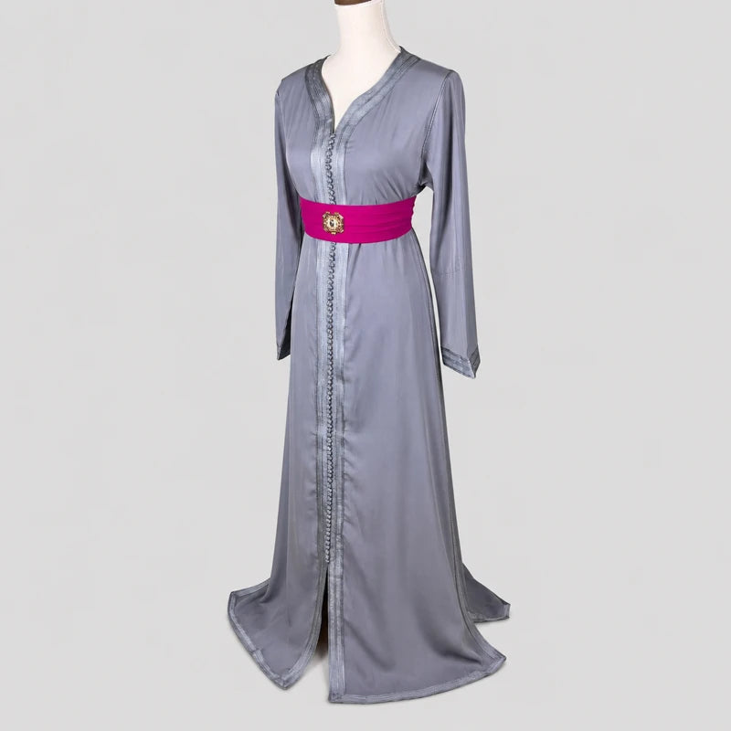 Caftan marocain simple gris en crêpe avec ceinture fuchsia et finitions traditionnelles, présenté en vue trois-quarts sur mannequin, robe longue élégante pour cérémonie, fête ou occasion spéciale.