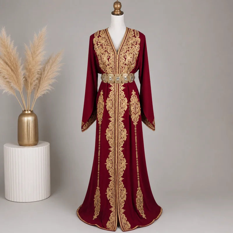 Caftan rouge en crêpe de soie avec broderies dorées et ceinture ornée, présenté sur mannequin dans un décor élégant avec vase et pampas, tenue idéale pour mariage et cérémonie orientale