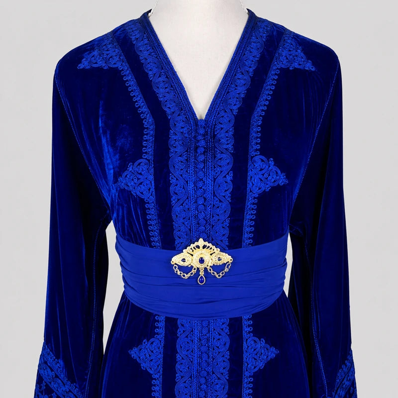Détail d’un caftan marocain femme en velours bleu royal avec broderies artisanales ton sur ton et ceinture élégante dorée.