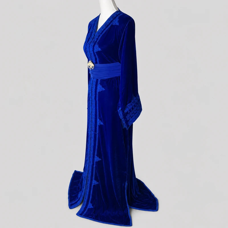Vue de profil d’un caftan marocain femme en velours bleu royal avec broderies raffinées et ceinture élégante style oriental traditionnel.