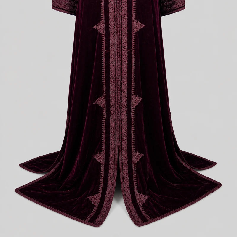 Détail du bas d’un caftan marocain en velours bordeaux avec broderies traditionnelles raffinées et tissu fluide élégant pour tenue orientale de cérémonie et mariage.