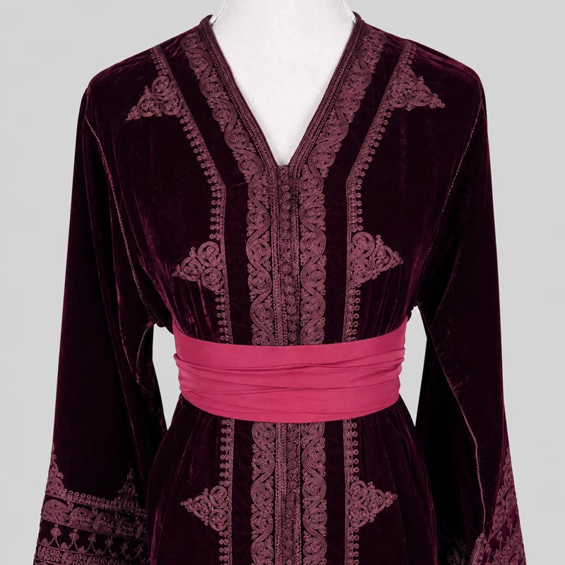 Détail brodé d’un caftan marocain en velours bordeaux avec ceinture rose satinée, finitions artisanales élégantes et col travaillé pour tenue traditionnelle raffinée.