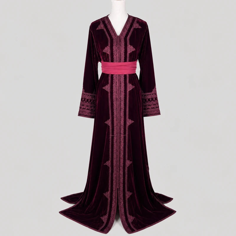 Caftan en velours bordeaux brodé pour femme avec ceinture rose satinée, coupe longue élégante et finitions marocaines raffinées pour mariage, fête et occasion spéciale.