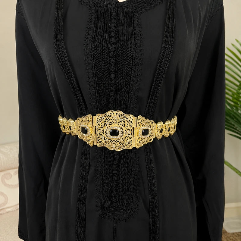 Ceinture marocaine dorée style mdamma avec pierres noires portée sur un caftan noir élégant pour mariage oriental et cérémonie