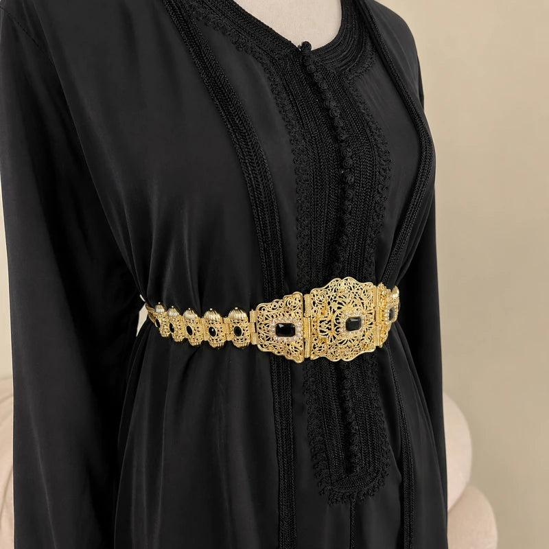 Ceinture marocaine dorée style mdamma avec pierres noires portée sur un caftan noir vue de côté