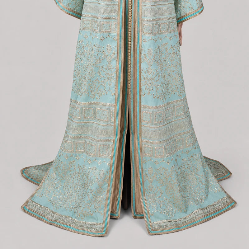 Gros plan sur les ornements dorés et le tissu brocard d'une takchita marocaine vert d'eau, robe caftan élégante pour mariage et cérémonie.