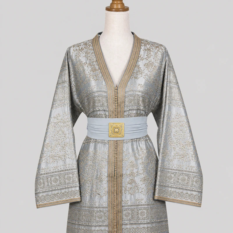 Détail du haut d’un caftan gris argenté en brocard avec motifs dorés et ceinture élégante, finition raffinée pour tenue orientale de mariage et cérémonie.