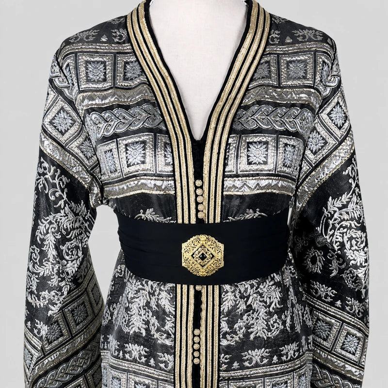 Détail du haut d’un caftan marocain brocart noir avec motifs argentés raffinés, ceinture noire élégante et finitions dorées artisanales.