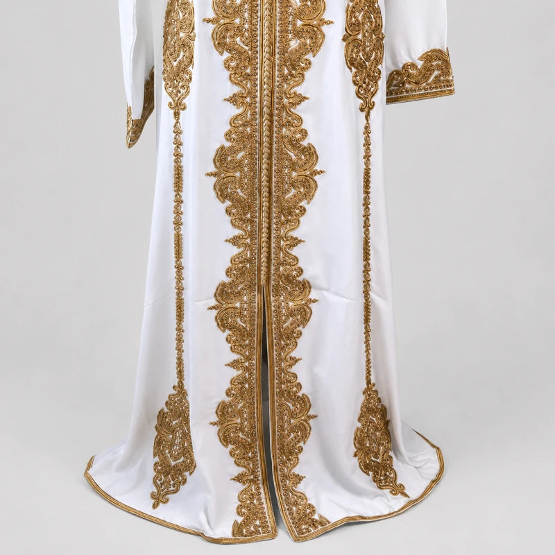 Détail du bas d’un caftan marocain blanc avec broderies dorées raffinées et finitions artisanales, robe orientale élégante pour mariage et cérémonie