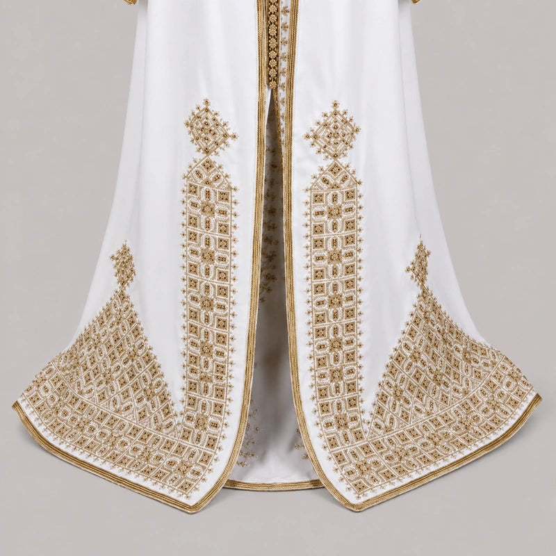 Détail du bas d’une takchita blanche Henna Tarz el Fassi avec broderies dorées géométriques et finition marocaine raffinée
