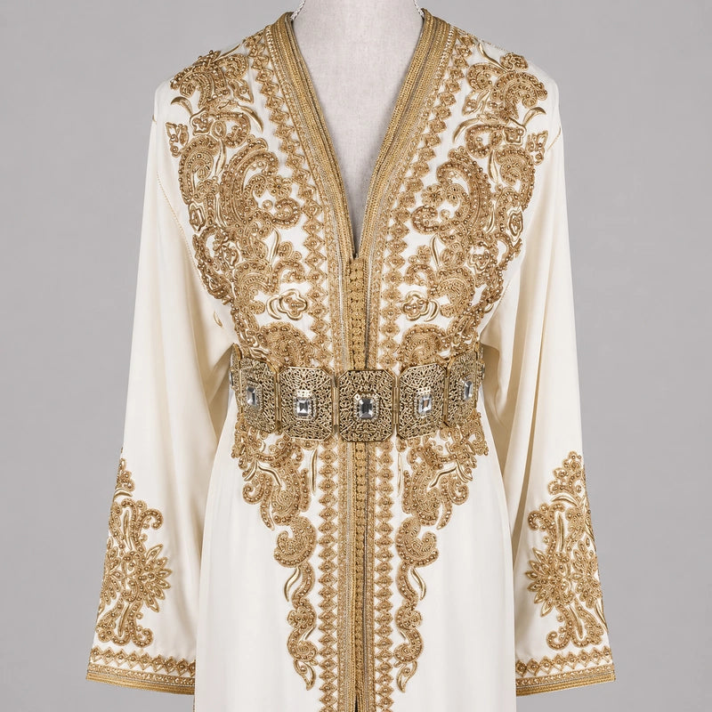 Détail du haut d’une takchita mariée blanc cassé en crêpe de soie avec broderies dorées luxueuses et ceinture raffinée