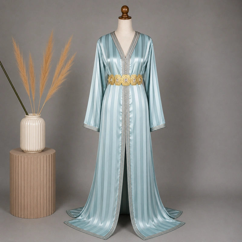 Takchita marocaine bleu givré en tlija avec rayures satinées et ceinture dorée dans une mise en scène élégante style oriental