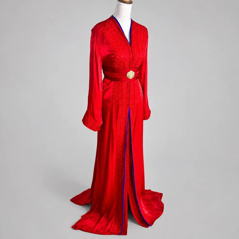 Vue de trois quarts d'une takchita marocaine rouge et bleu roi en organza de mariage avec broderies artisanales et ceinture traditionnelle, idéale pour cérémonie et mariage.