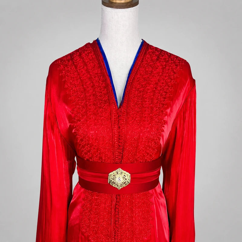 Détail du buste d'une takchita marocaine rouge et bleu roi en organza de mariage, mettant en valeur les broderies artisanales, le col en V et la ceinture traditionnelle.