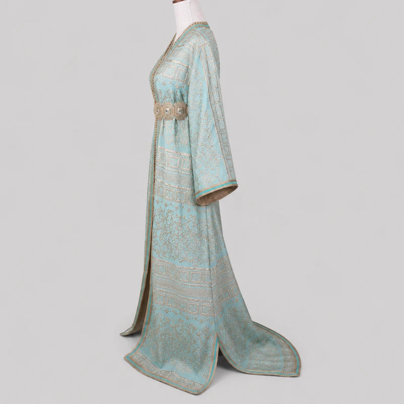 Vue latérale d'une takchita marocaine vert d'eau en brocard brodé doré avec ceinture traditionnelle, mettant en valeur la coupe élégante et les finitions artisanales.